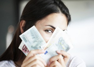 Woman peeking behind euro notes